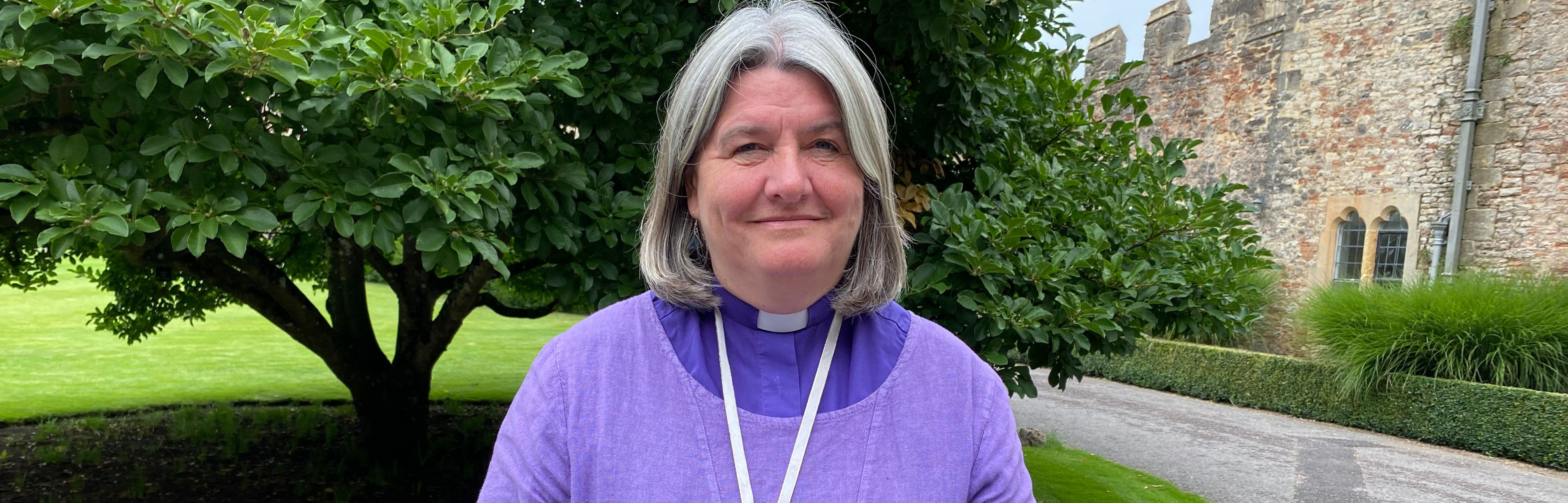 Bishop Ruth standing in front of the Magnolia tree at the Bishop's Palace, Wells